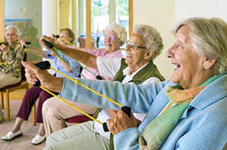A class of older adults sit while pulling exercise bands.